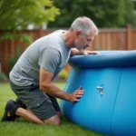 Homme redressant une piscine autoportée qui penche dans un jardin résidentiel